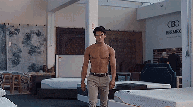 a shirtless man is walking in a store with mattresses and a sign that says bermex