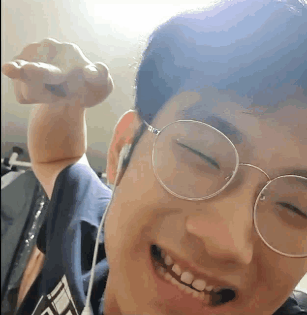 a young man wearing glasses and headphones is smiling and pointing