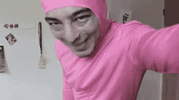 a man in a pink suit is taking a selfie in a kitchen .