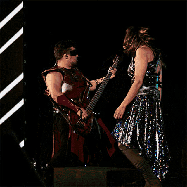a man is playing a guitar next to a woman