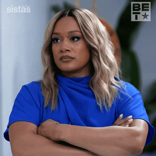 a woman in a blue shirt is standing with her arms crossed