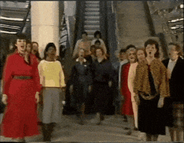 a group of women singing in front of an escalator .