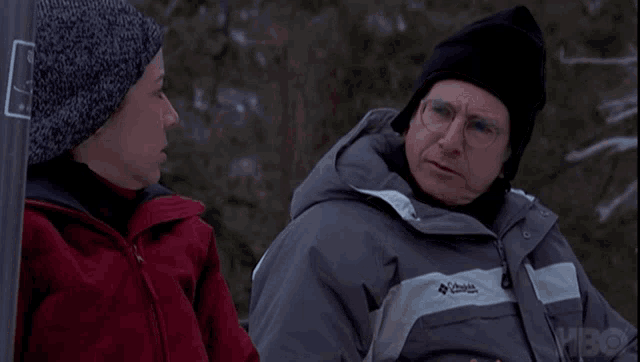 a man wearing a columbia jacket talks to a woman