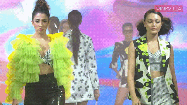two women are walking down a runway with a pinkvilla logo in the corner