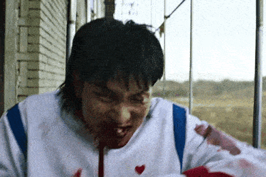 a man with blood on his face is holding a bloody object in his hand .
