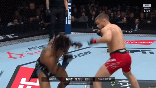 two men are fighting in a boxing ring with the ufc logo on the wall behind them