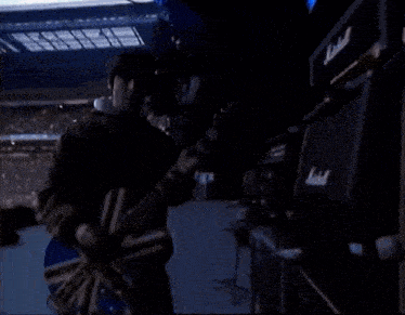 a man is playing a guitar in front of a crowd in a stadium