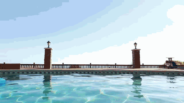a swimming pool surrounded by a fence and two pillars