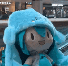 a stuffed animal wearing a blue hat and gloves is sitting on a escalator .