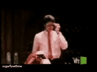a man in a white shirt and red tie is standing in front of a vh1 logo