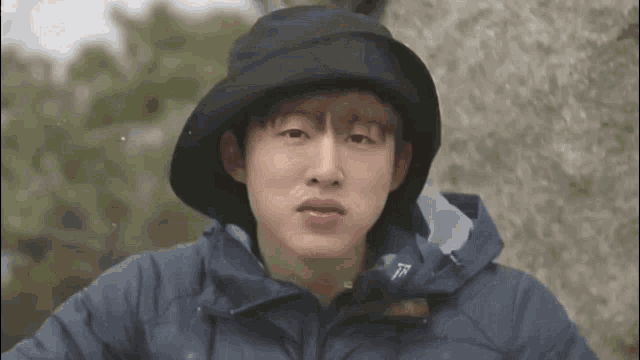 a man wearing a hat and a jacket is making a funny face .