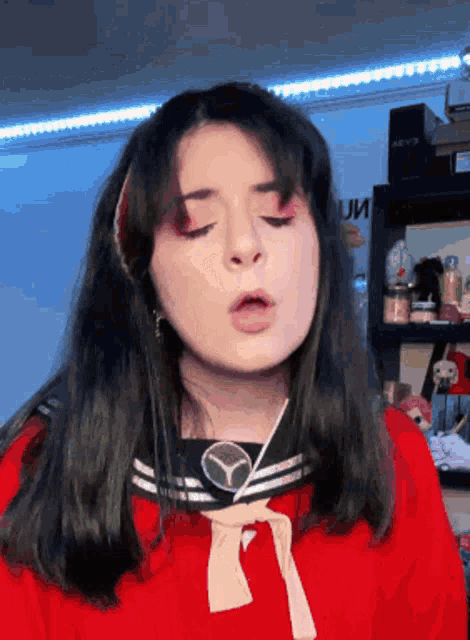 a girl wearing a red shirt with a mercedes logo on the front