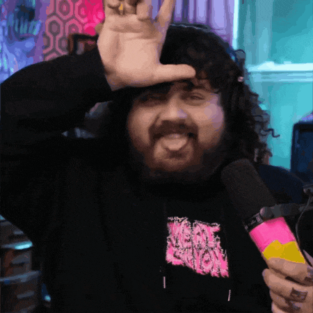 a man with a beard is holding a microphone and making a devil horn sign