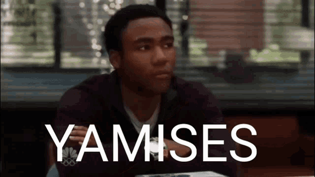a man sitting at a table with the word yamises written on the screen behind him