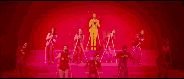 a man in a yellow suit is surrounded by a group of people in red suits