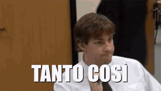 a man in a white shirt and tie is sitting in front of a sign that says tanto così