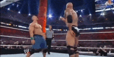 two men are wrestling in a wrestling ring and one of them is wearing a w logo on his belt .