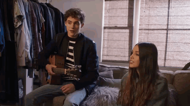 a man is playing a guitar while a woman sings .