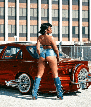 a woman in shorts and boots stands in front of a red car with a license plate that says ' nc ' on it