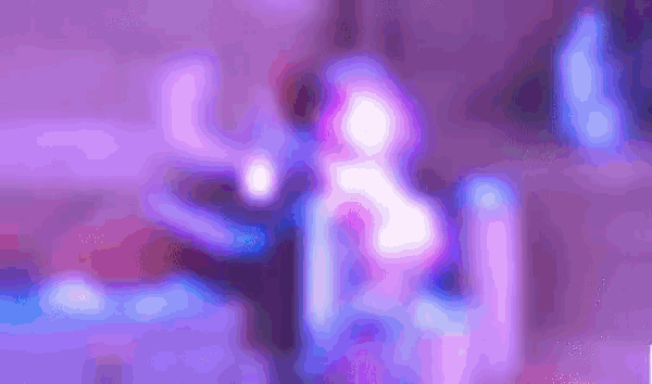 a blurry picture of a woman dancing in a club with purple lights .