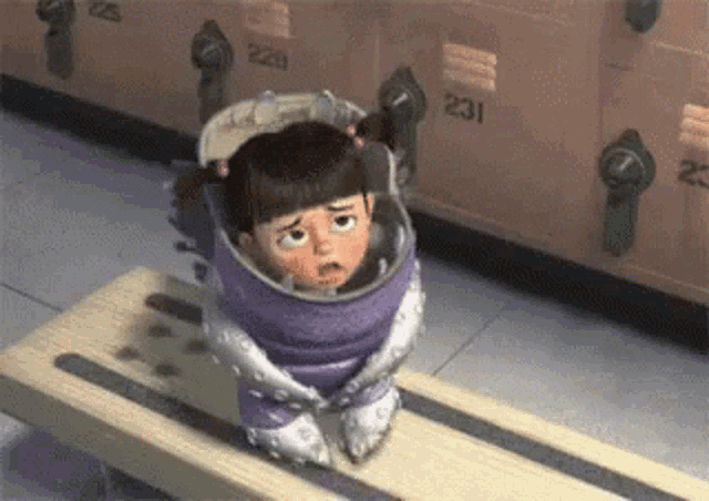 boo from monsters inc is wrapped in a purple blanket and sitting on a wooden bench .