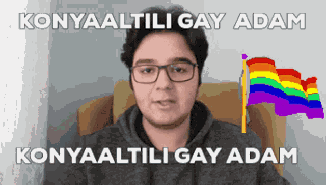 a man with glasses is sitting in a chair next to a rainbow flag with the words konyaaltili gay adam written on it