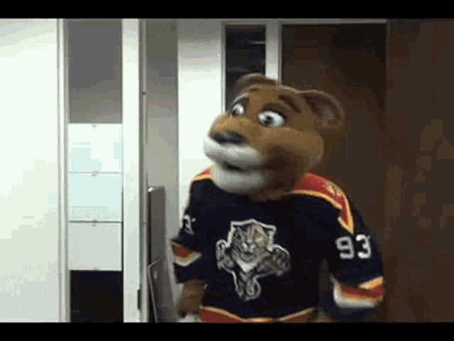 a mascot wearing a jersey with the number 93 is standing in a doorway .