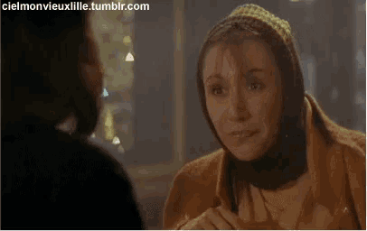 a woman wearing a head scarf is talking to a man in a dark room .