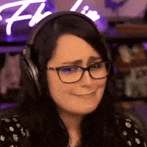 a woman wearing headphones and glasses is smiling and making a funny face .