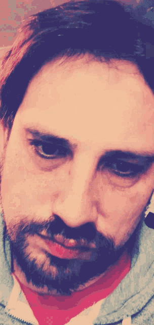 a close up of a man 's face with a beard and red shirt