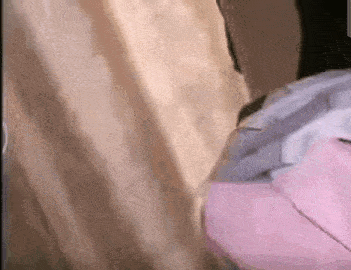 a close up of a person in a pink dress standing next to a curtain .