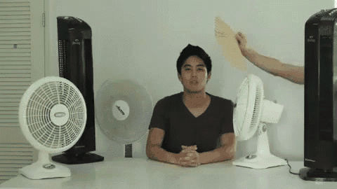 a man sitting at a table with a fan that says ' emerson ' on it