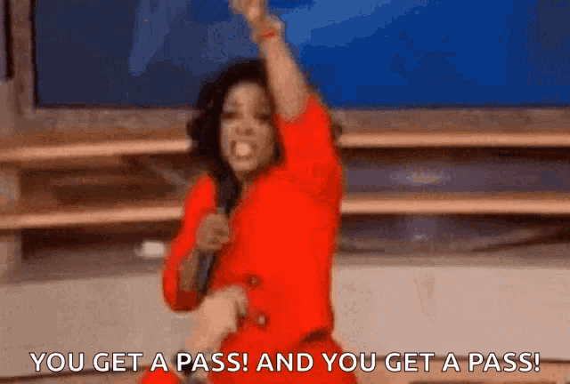 a woman in a red dress is holding a microphone and saying you get a pass