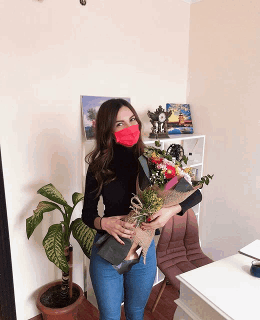 a woman wearing a red face mask holds a bouquet of flowers
