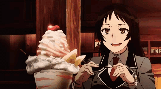 a girl is sitting in front of a bowl of ice cream with a cherry on top