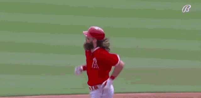 a baseball player with a beard is running on a baseball field .