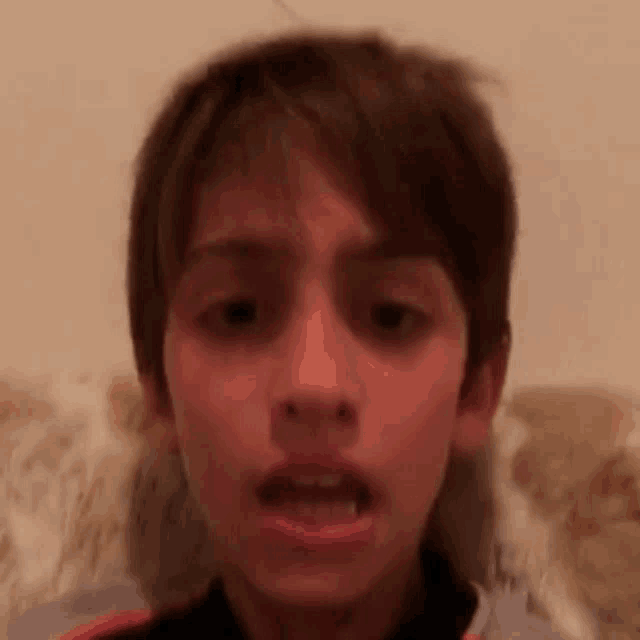 a close up of a young boy making a funny face