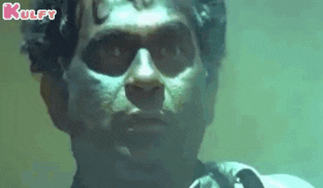 a close up of a man 's face in a dark room with the word kulfy on the bottom .