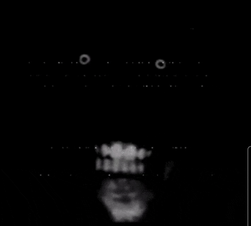 a black and white photo of a person 's face with a beard and teeth in the dark .