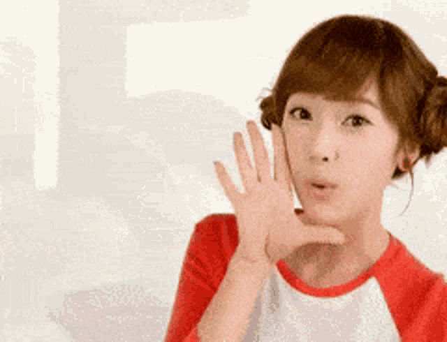 a girl in a red and white shirt is waving