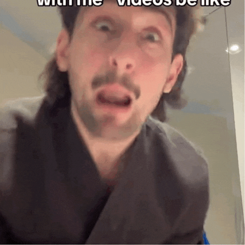 a man with a mullet and a beard is making a funny face with the words with the videos be like below him