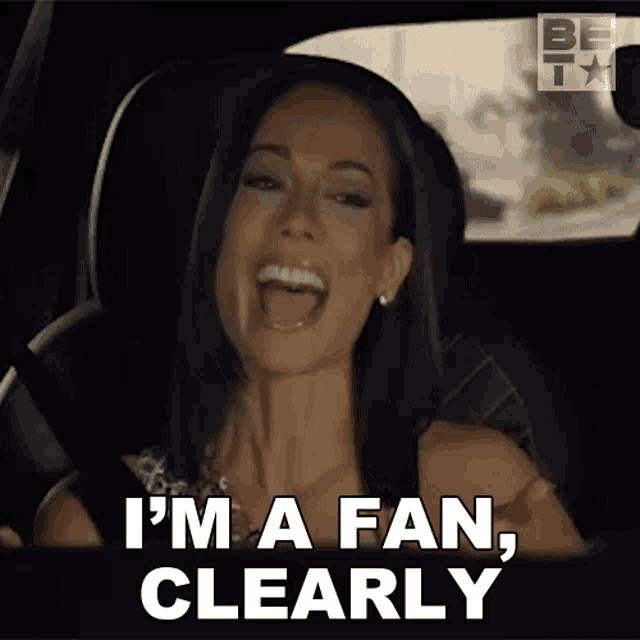 a woman is sitting in a car with her mouth open and says i 'm a fan clearly