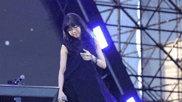 a woman in a black dress is singing into a microphone on stage