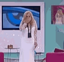 a woman in a white dress is covering her face in front of a television .