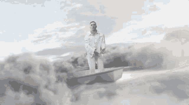a man in a white suit is standing in a boat in the clouds .
