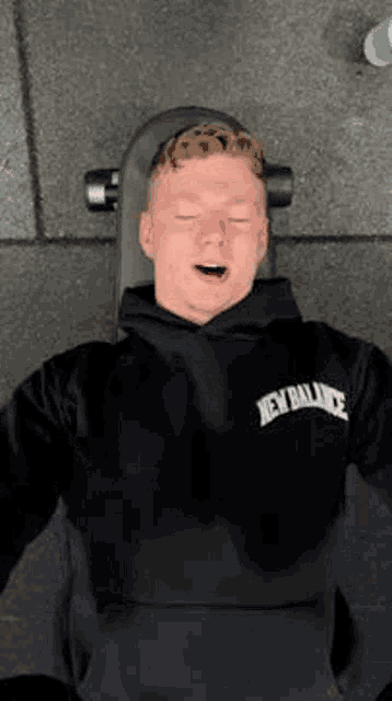a young man is laying on a bench in a gym with his eyes closed .