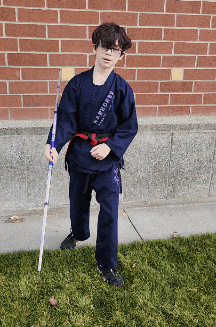 a young boy in a karate uniform is holding a stick