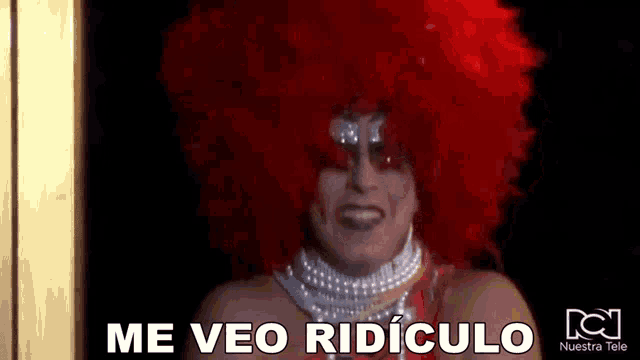 a drag queen wearing a red wig and a pearl necklace is making a funny face .