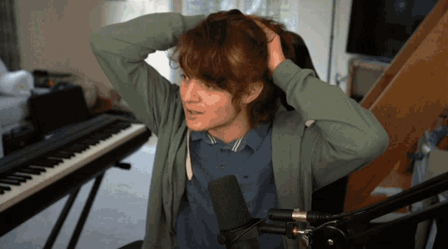 a person sitting in front of a microphone holding their head