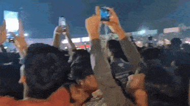 a crowd of people are holding up their phones in the air
